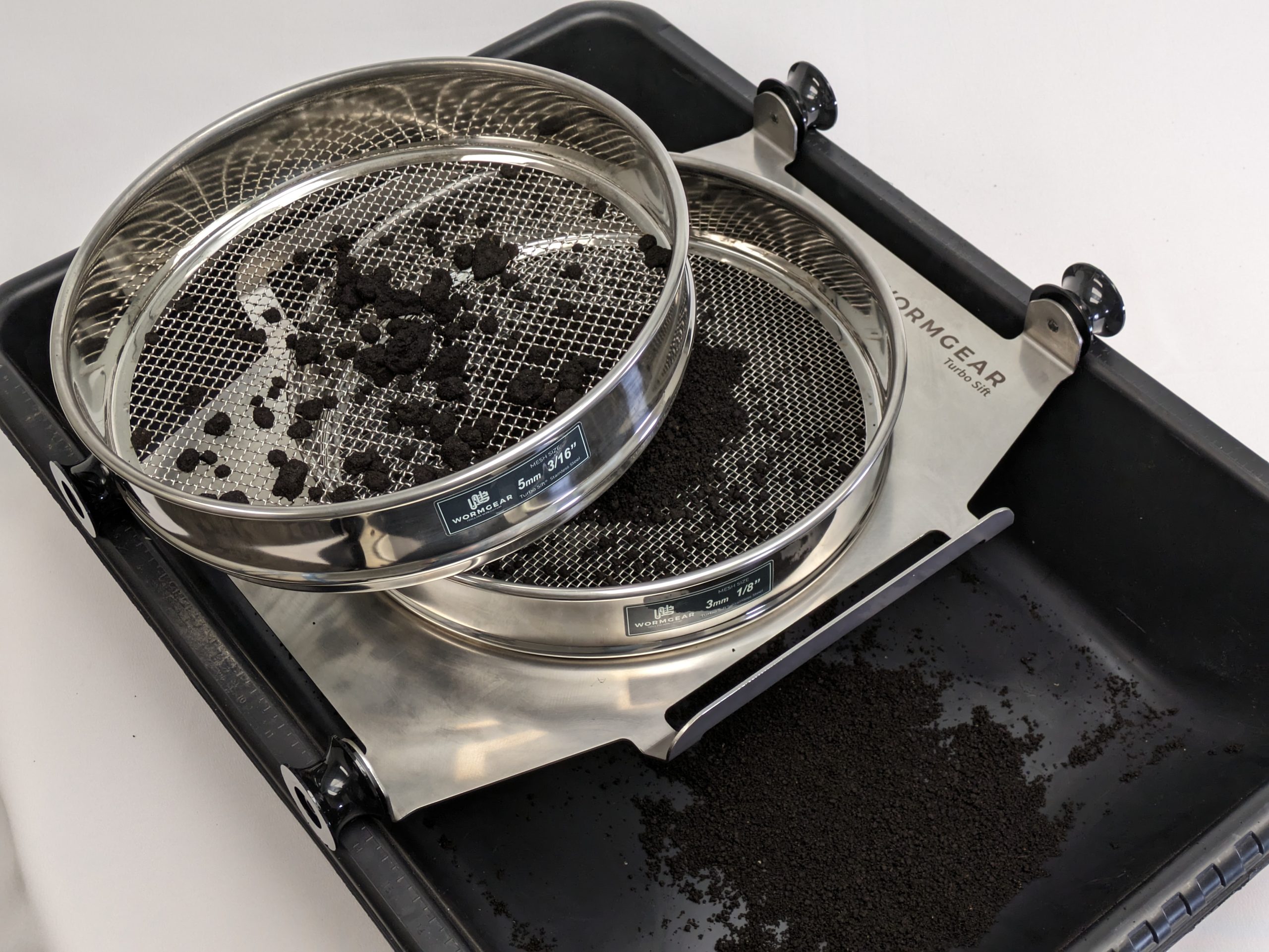 Sifting worm castings using the Wormgear Turbo Sift™ Wormgear Turbosift with dual stainless steel sieves for compost refining, showing separated compost material in a black collection tray, emphasizing its use in producing high-quality, uniform compost.